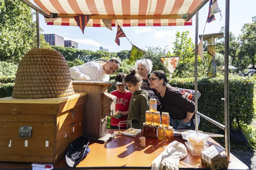 Kinderen en volwassenen bij honing kraam eilandsteede met imker