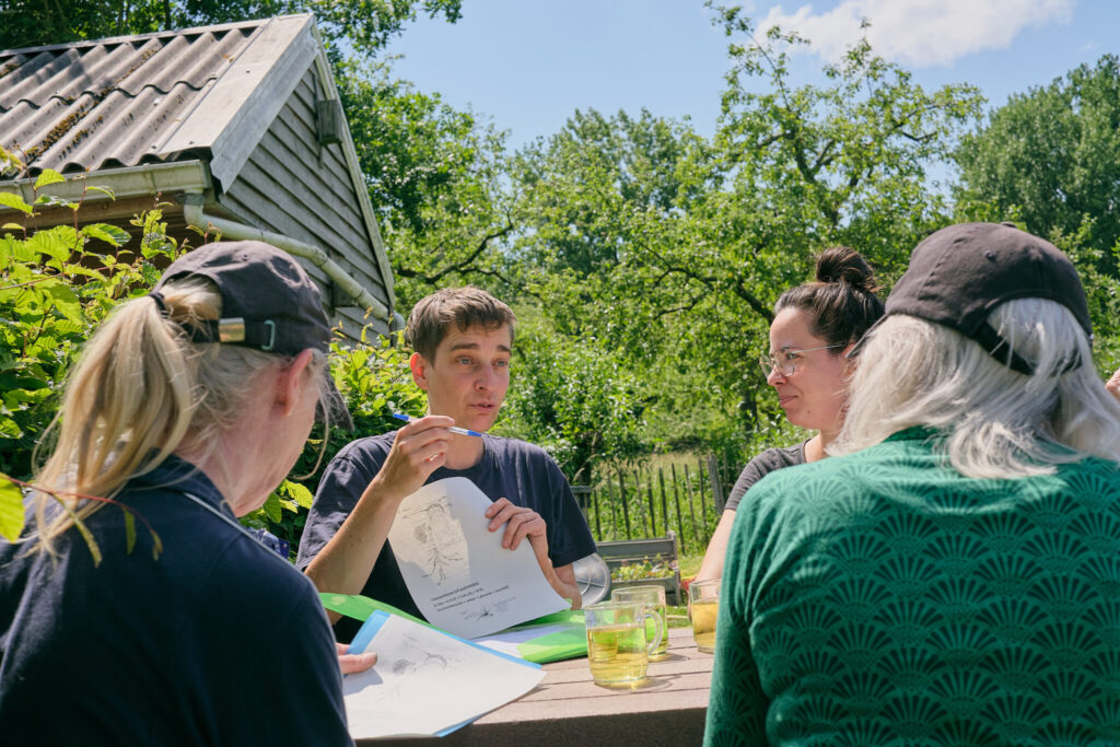 Moestuinexpert Mariken Heitman met cursisten aan tafel.