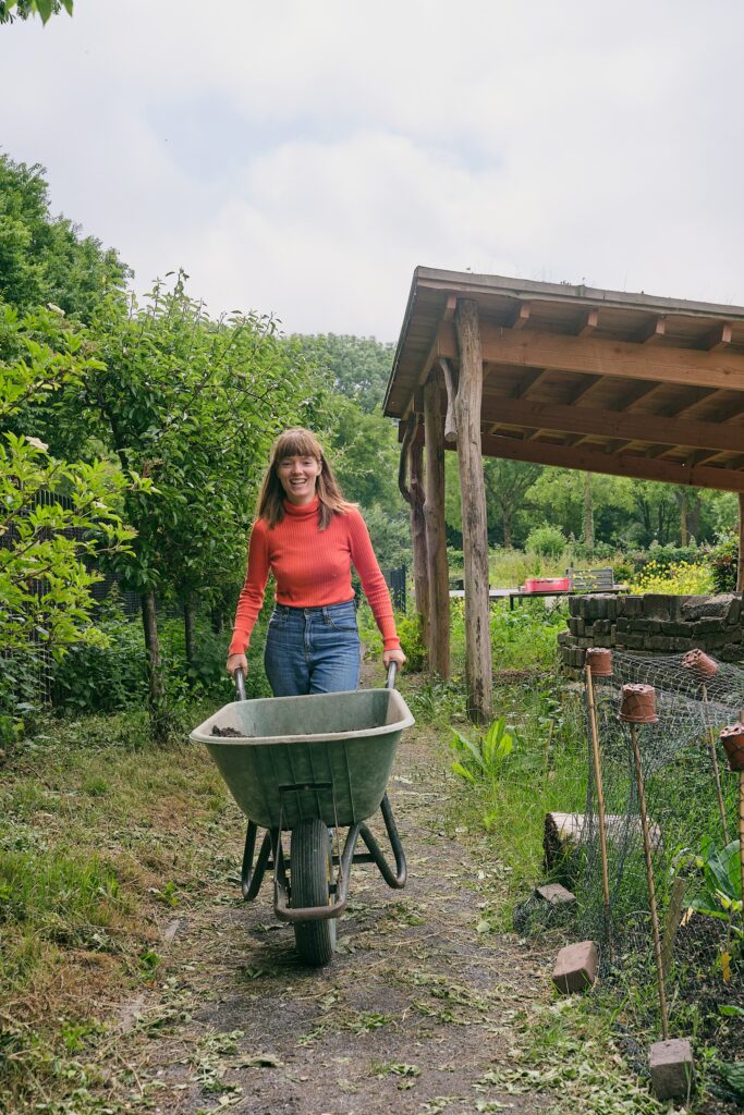 persoon met kruiwagen in de moestuin van stadsboerderij eilandsteede stadstuin